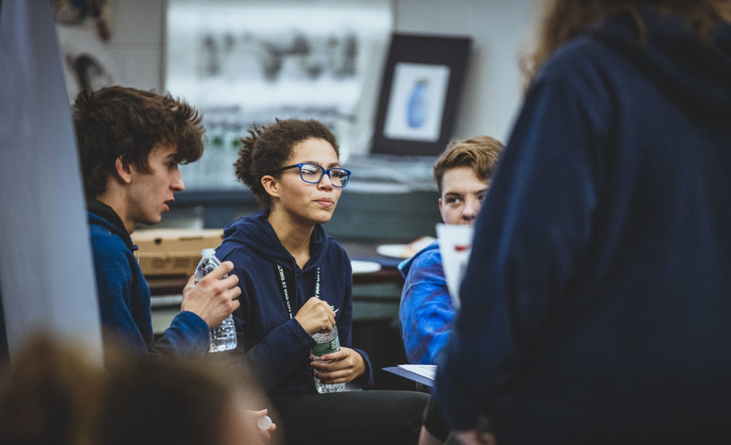 High school students sitting together at a table, discussing class.